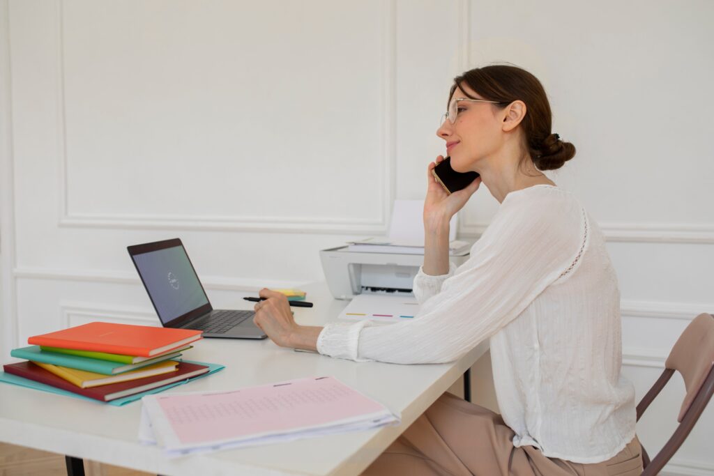 A woman talking on a phone while sitting at her desk