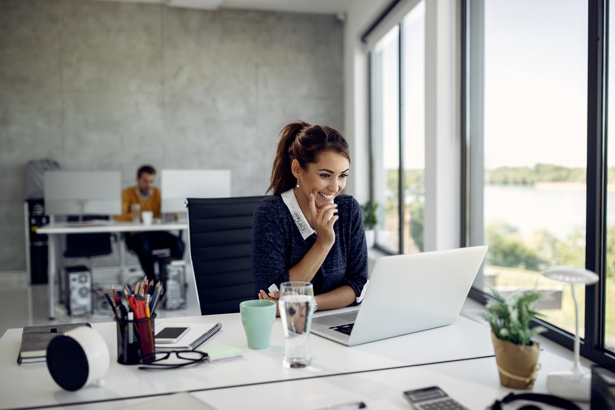 A woman at a desk uses her laptop